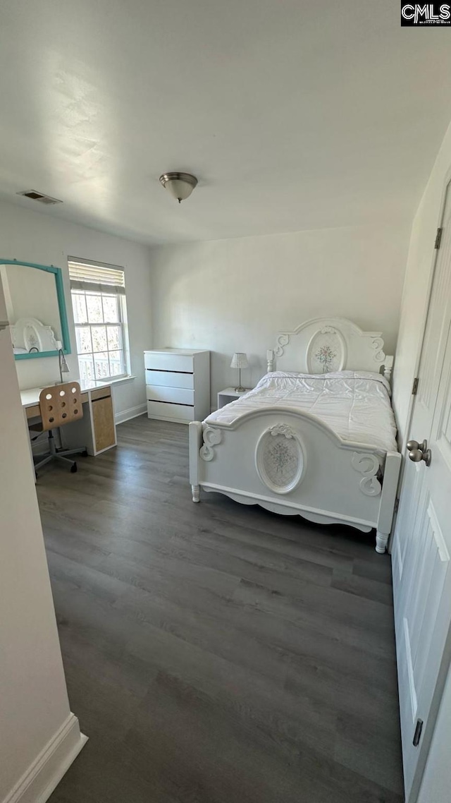 bedroom with visible vents, baseboards, and wood finished floors