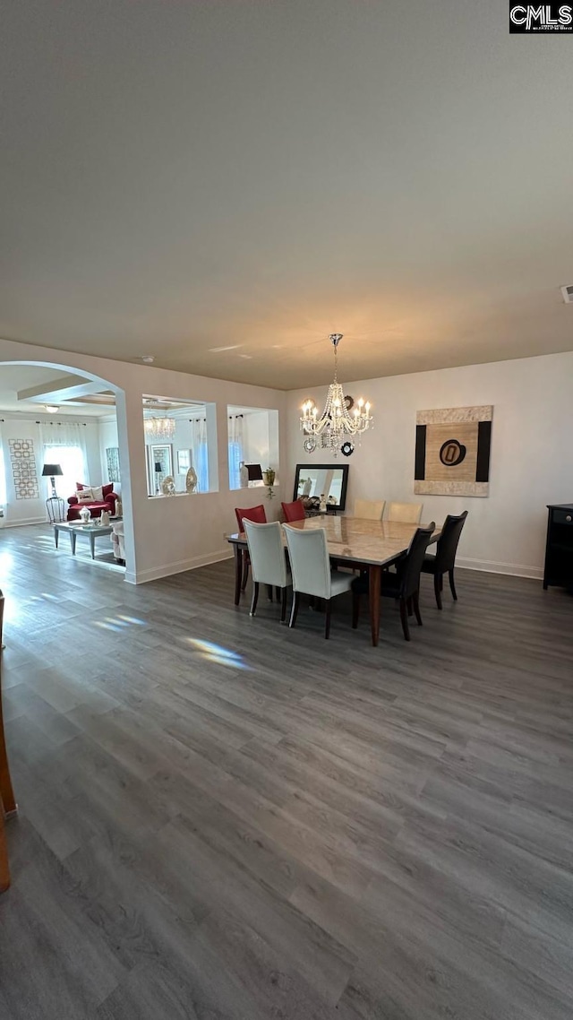 dining area with dark wood finished floors, a notable chandelier, visible vents, and baseboards