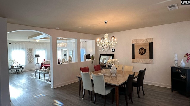 dining space featuring dark wood finished floors, visible vents, a notable chandelier, and baseboards