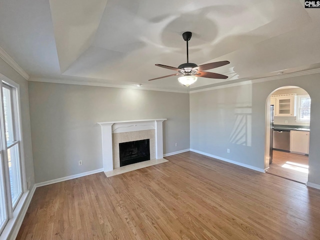 unfurnished living room with ornamental molding, a tile fireplace, and light wood finished floors