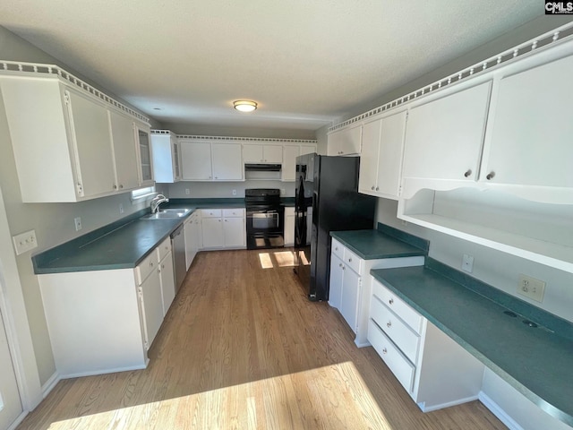 kitchen with a sink, dark countertops, black appliances, and light wood finished floors