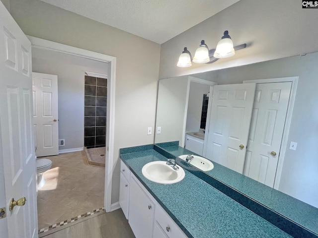 full bath featuring vanity, tile patterned floors, baseboards, and a textured ceiling