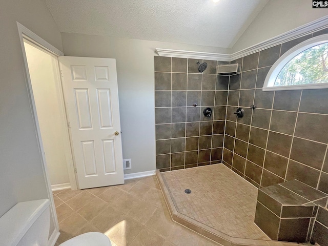 bathroom featuring tiled shower, lofted ceiling, a textured ceiling, tile patterned floors, and toilet