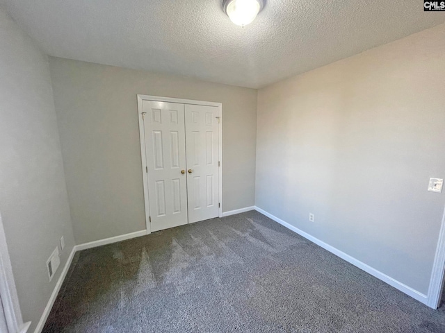 unfurnished bedroom featuring visible vents, baseboards, a closet, and dark carpet