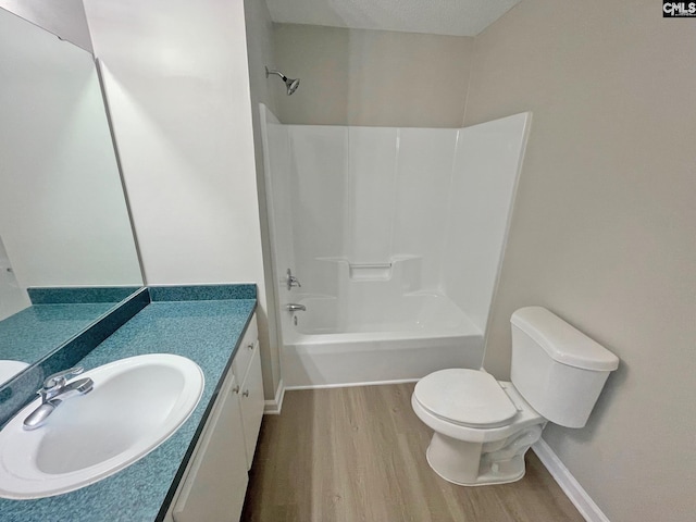 bathroom with tub / shower combination, baseboards, toilet, wood finished floors, and vanity