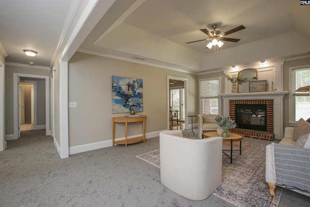 living room with baseboards, carpet floors, a tray ceiling, ornamental molding, and a brick fireplace