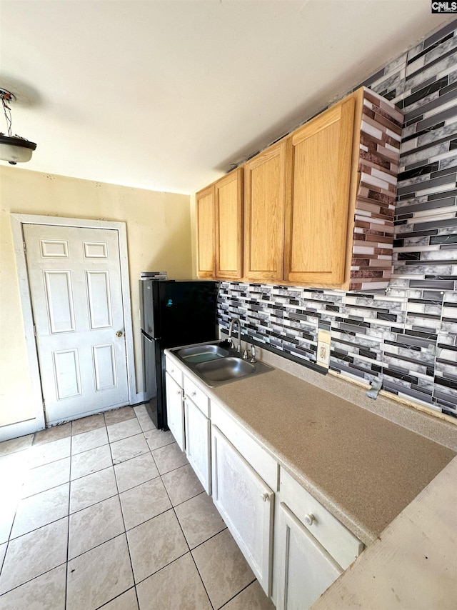 kitchen with a sink, decorative backsplash, light countertops, and light tile patterned floors