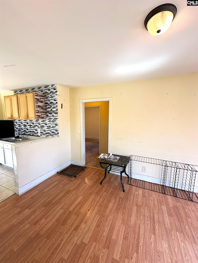 unfurnished room featuring light wood-style flooring, baseboards, and a sink