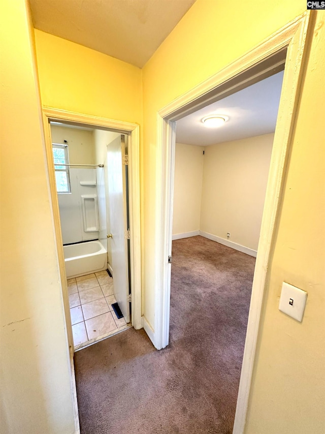 corridor featuring baseboards, carpet, and tile patterned flooring