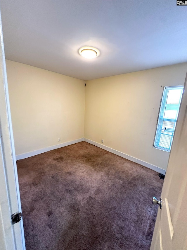 carpeted spare room featuring baseboards