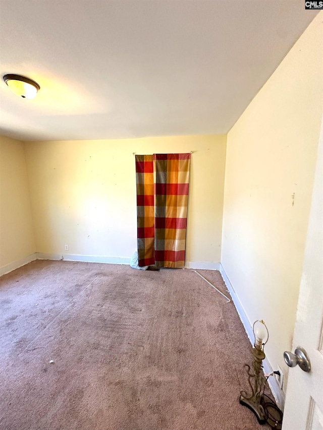 empty room featuring baseboards and carpet