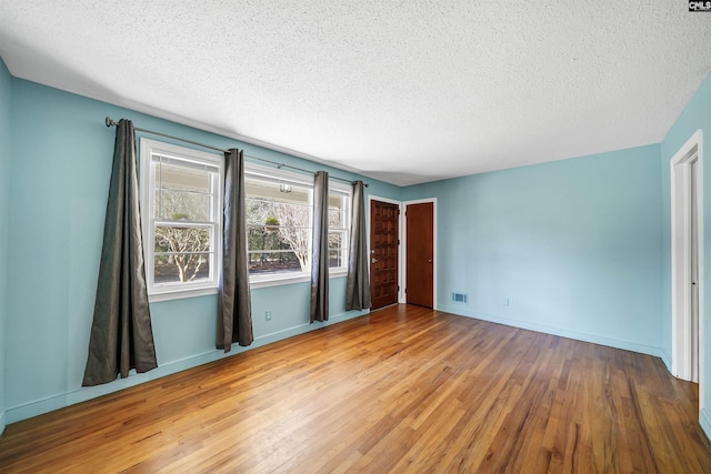 unfurnished bedroom with wood finished floors, visible vents, and baseboards