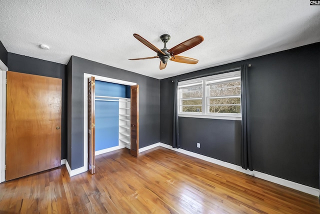 unfurnished bedroom featuring a textured ceiling, wood finished floors, a closet, and baseboards