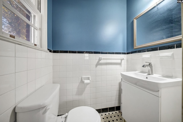 bathroom featuring vanity, tile walls, and toilet