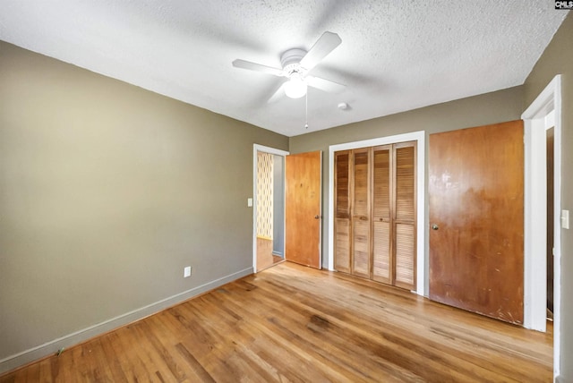 unfurnished bedroom featuring a textured ceiling, a ceiling fan, baseboards, and wood finished floors