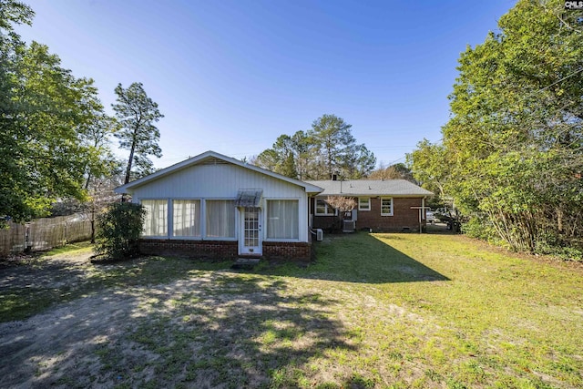 rear view of property featuring fence, a lawn, and brick siding