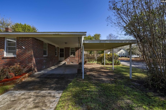 exterior space with a carport, brick siding, driveway, and crawl space