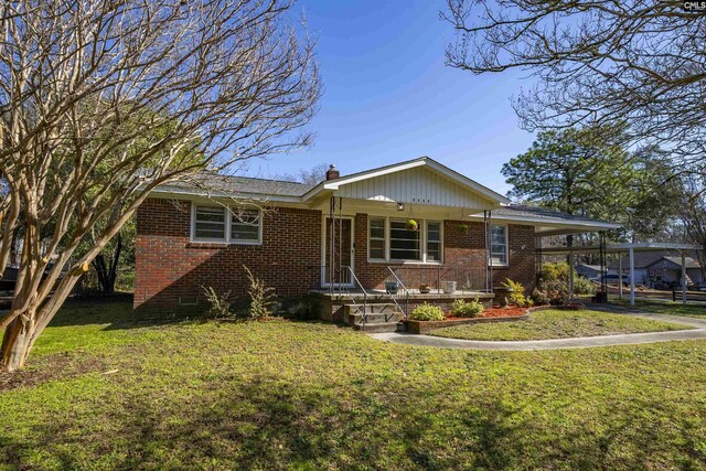 ranch-style home featuring brick siding, an attached carport, and a front yard