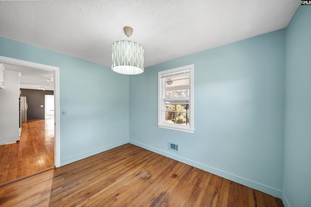 unfurnished room featuring light wood finished floors, visible vents, and baseboards