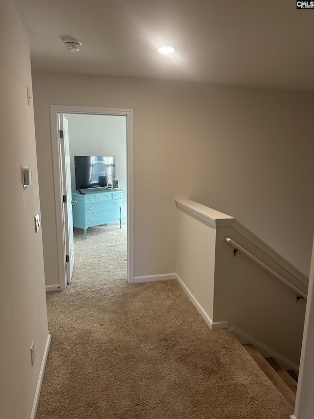 hall featuring an upstairs landing, baseboards, and light carpet