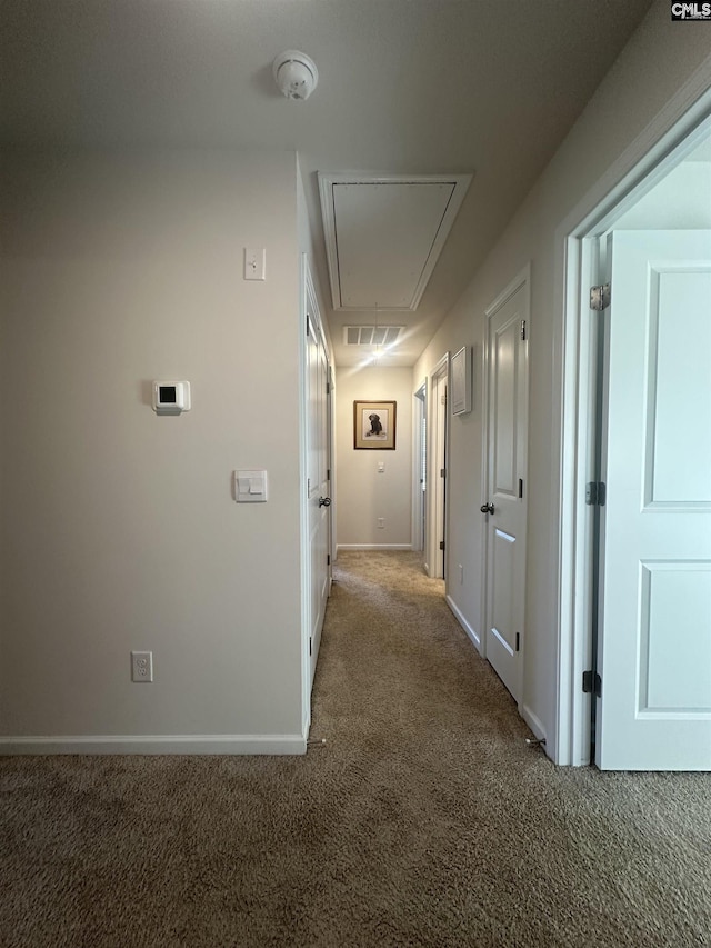 hallway featuring attic access, carpet, baseboards, and visible vents