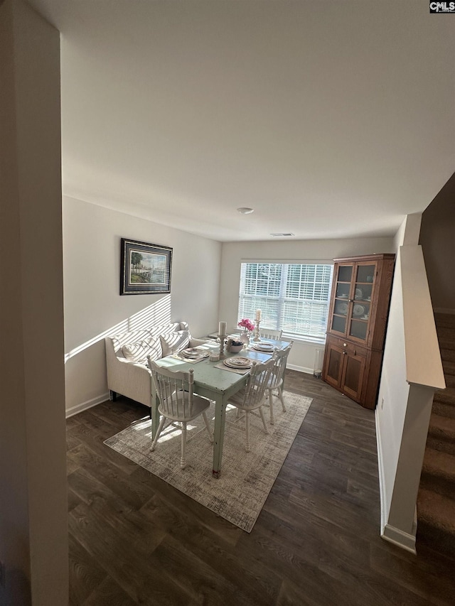 dining room featuring dark wood finished floors, stairs, and baseboards