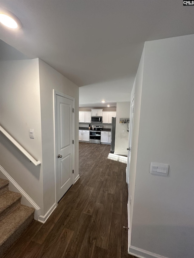 corridor featuring stairway, baseboards, and dark wood-style flooring