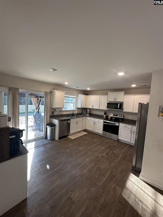 kitchen featuring dark wood-type flooring, dark countertops, white cabinetry, recessed lighting, and appliances with stainless steel finishes