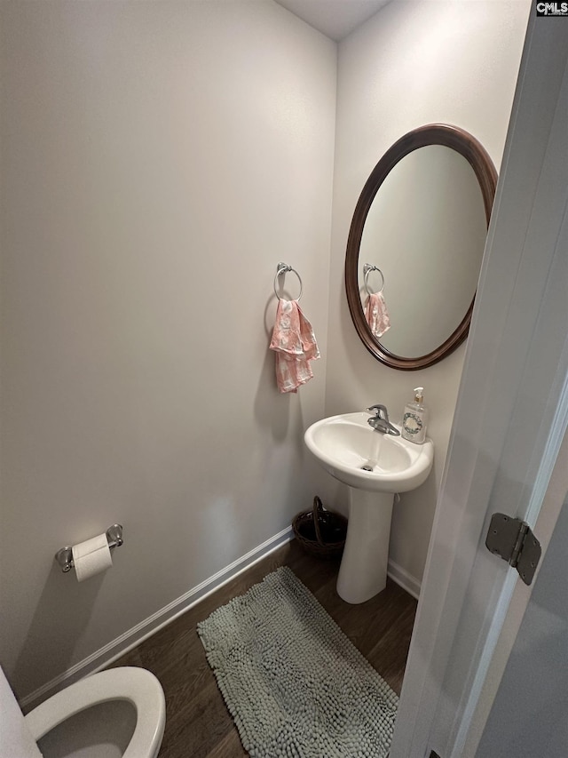 bathroom with baseboards, toilet, and wood finished floors