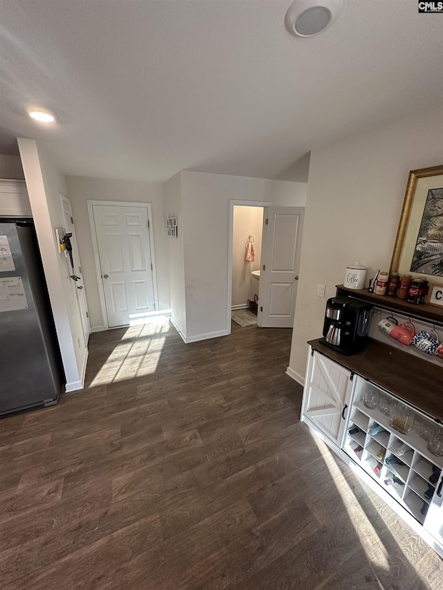 corridor featuring visible vents, baseboards, and dark wood-type flooring