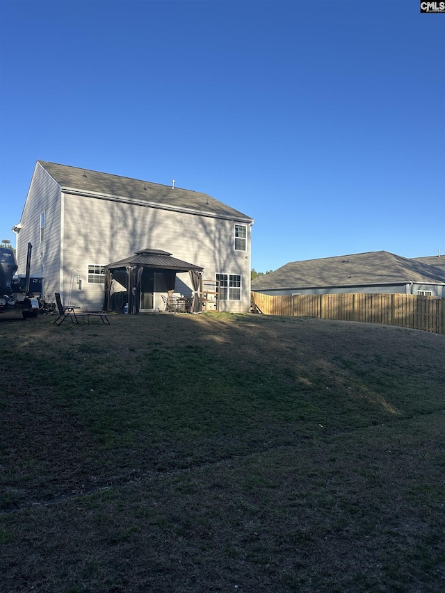 back of house with a gazebo, a yard, and a fenced backyard