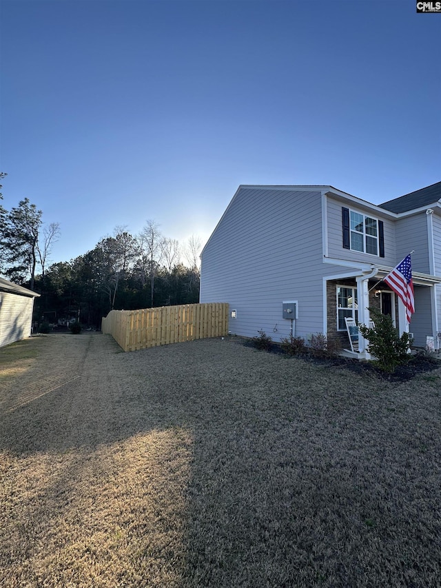 view of side of home featuring a lawn, driveway, and fence