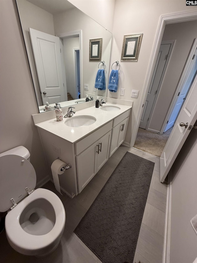 bathroom with double vanity, toilet, and a sink