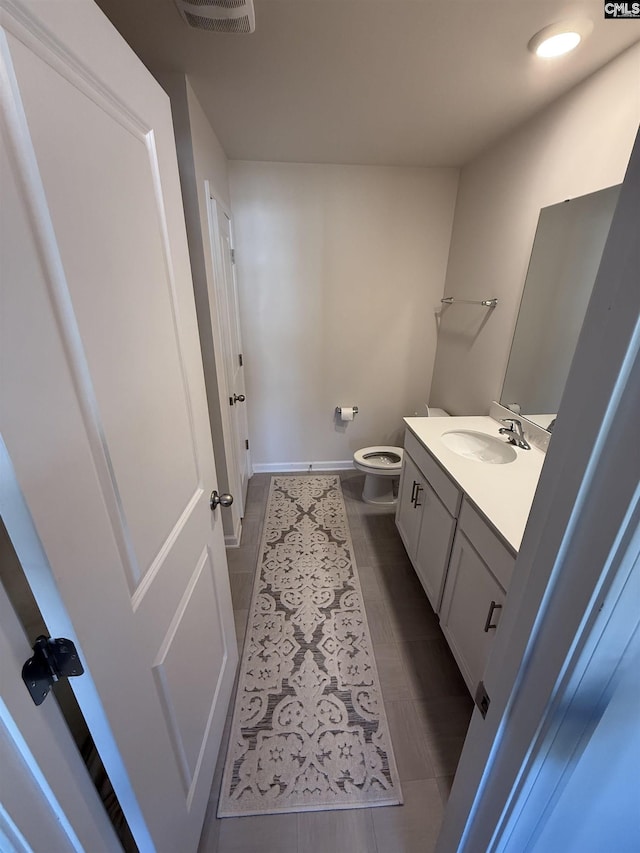 bathroom with visible vents, baseboards, toilet, and vanity