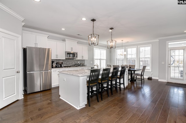 263 Compass Trl, Blythewood, SC 29016 - kitchen featuring dark wood finished floors, an island with sink, appliances with stainless steel finishes, crown molding, and a notable chandelier