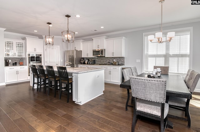 263 Compass Trl, Blythewood, SC 29016 - kitchen with a kitchen island with sink, ornamental molding, white cabinetry, stainless steel appliances, and a chandelier