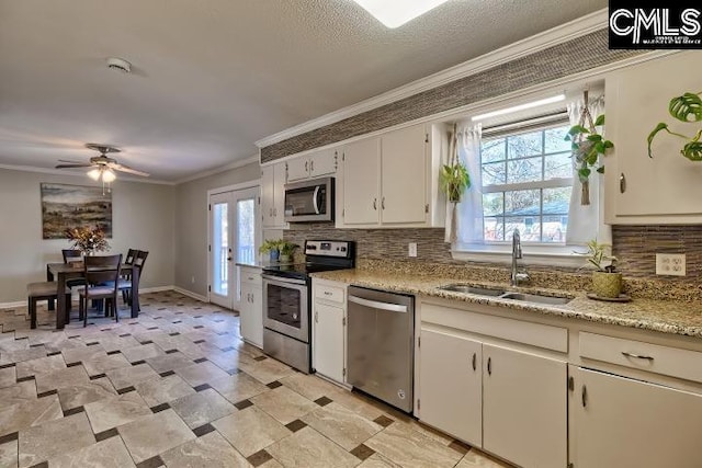 kitchen with a sink, stainless steel appliances, tasteful backsplash, and ornamental molding