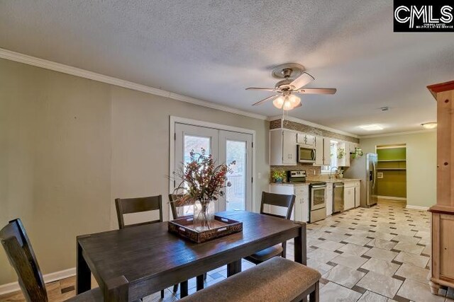 dining space with a ceiling fan, baseboards, a textured ceiling, and crown molding