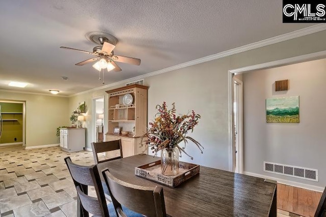 dining room with baseboards, visible vents, ceiling fan, a textured ceiling, and crown molding