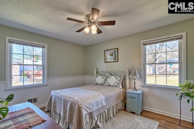 bedroom with light wood-style flooring, baseboards, visible vents, and a textured ceiling