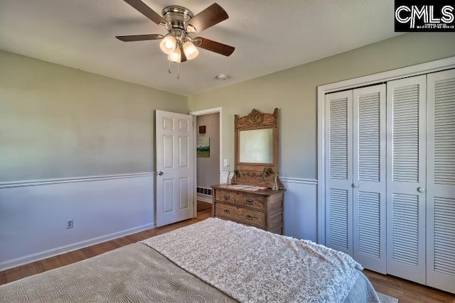 bedroom featuring a closet, baseboards, wood finished floors, and a ceiling fan