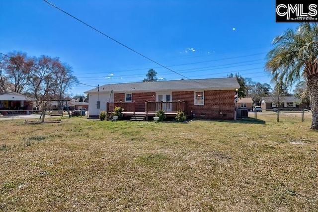 back of property featuring brick siding, fence, a wooden deck, a yard, and crawl space