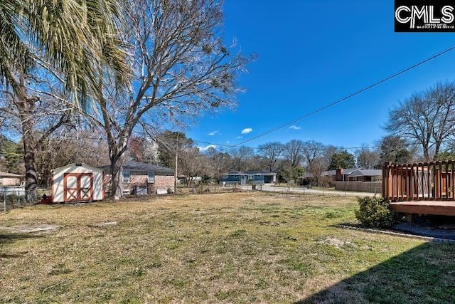 view of yard featuring an outbuilding, fence, and a shed