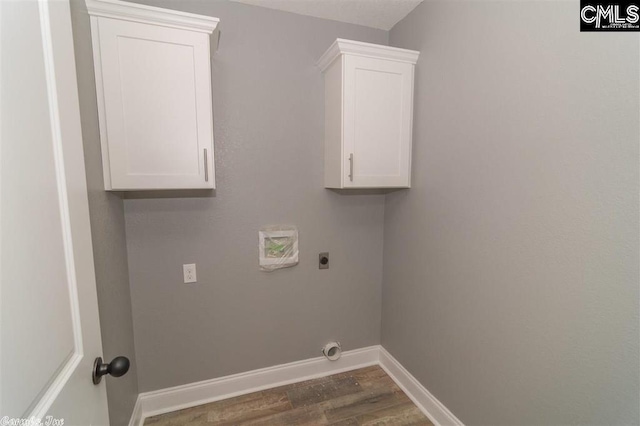 washroom featuring electric dryer hookup, baseboards, wood finished floors, and cabinet space