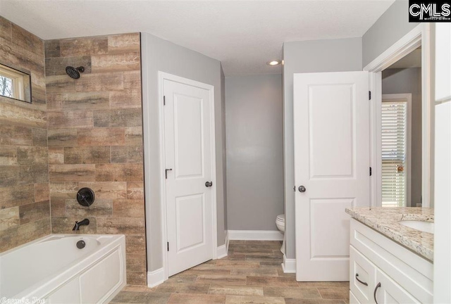 bathroom featuring wood finish floors, toilet, baseboards, bathtub / shower combination, and vanity