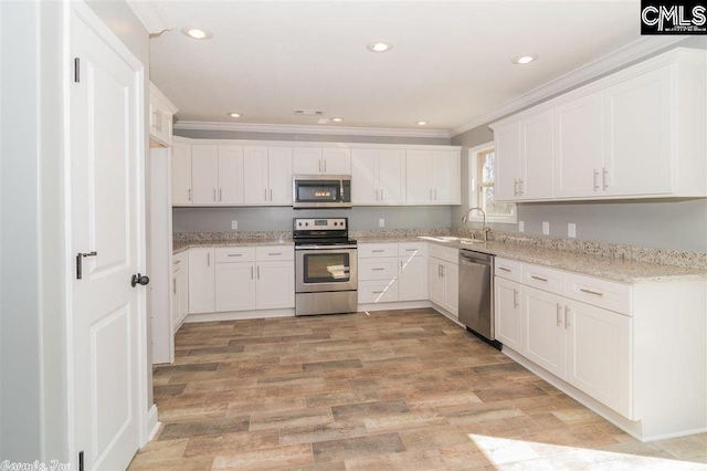 kitchen with appliances with stainless steel finishes, ornamental molding, and white cabinetry