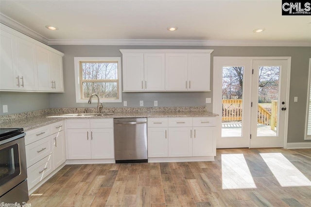 kitchen with stainless steel appliances, white cabinets, crown molding, and light wood-style flooring