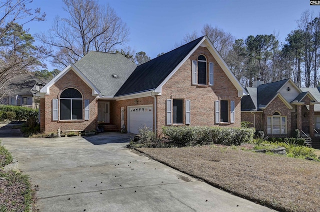 traditional-style home featuring brick siding, an attached garage, driveway, and roof with shingles