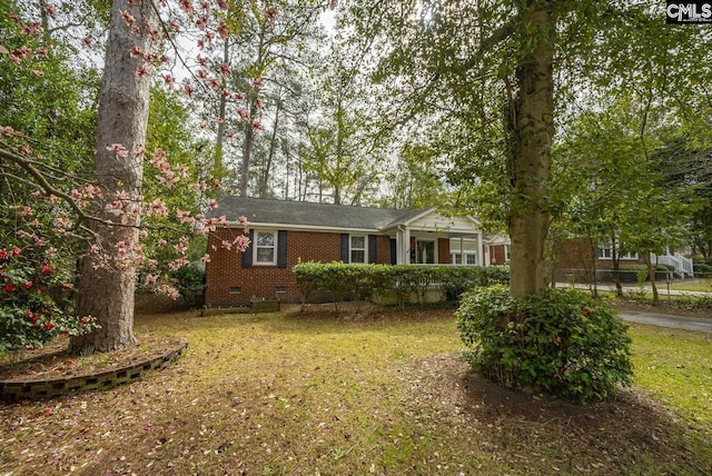 view of front facade featuring crawl space, brick siding, and a front yard