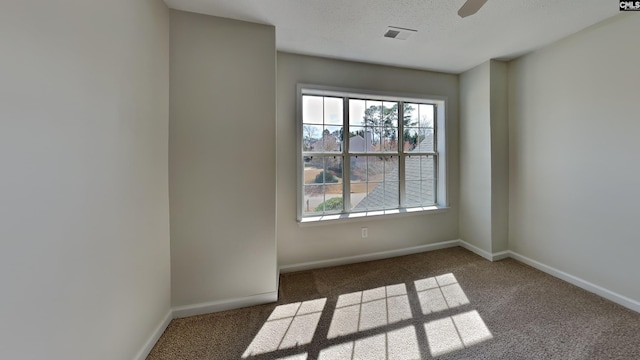 carpeted empty room with a ceiling fan, baseboards, visible vents, and a textured ceiling